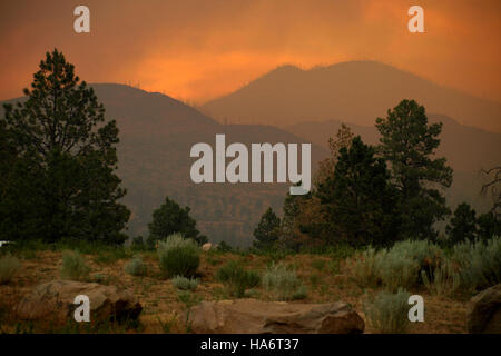 Un tramonto pieno di fumo sulle montagne Jemez, fotografato durante un incendio nel giugno 2011. L'incendio ha colpito la regione e l'immagine cattura la dura bellezza di un disastro naturale, con un forte fumo che gira attraverso il cielo, proiettando una spettacolare vista del tramonto. Foto Stock