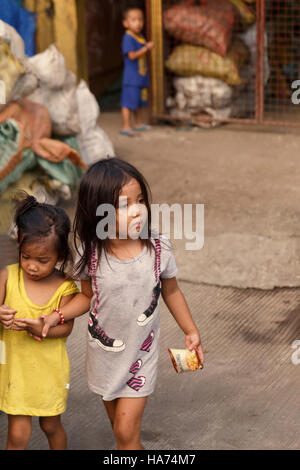 CEBU, FILIPPINE-ottobre 18,2016: bambina si prende cura di sua sorella nel mercato del carbonio su ottobre 18, Cebu, Filippine. Foto Stock