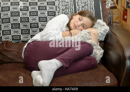 Pre adolescente si siede sul divano in casa Foto Stock