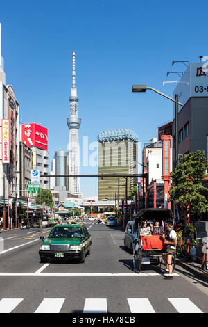 Un taxi e un rickshaw fianco a fianco con il Tokyo Skytree in background in Asakusa, Tokyo, Giappone. Foto Stock