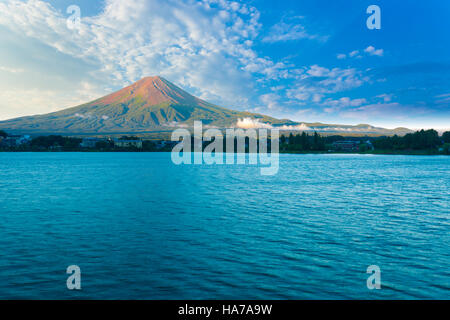 Il monte Fuji bagna nella mattina di luce laterale mentre il lago Kawaguchiko siede in ombra sotto nuvoloso cielo blu su un giorno di estate, cinque laghi Foto Stock