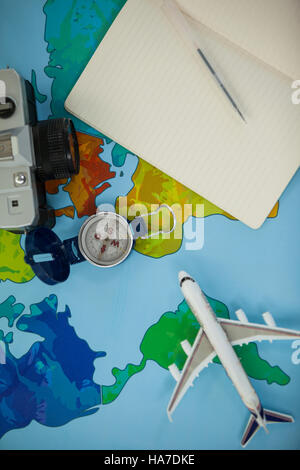 Fotocamera digitale, latteria, penna, mappa, bussola e modello di aeroplano su tavola Foto Stock