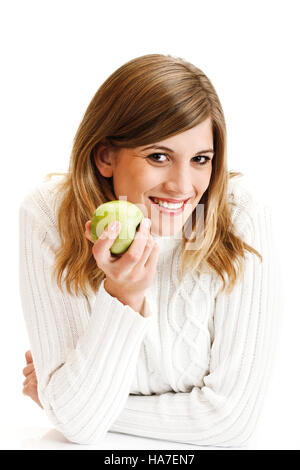 Giovane donna in un bianco maglione turtleneck azienda mela verde Foto Stock