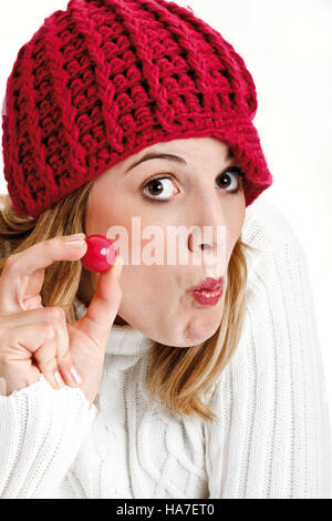 Giovane donna in un bianco turtleneck maglione rosso con cappello di lana e gomme da masticare la sfera Foto Stock