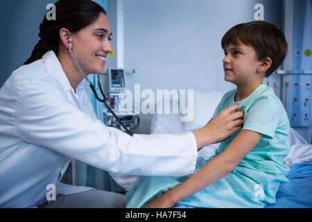 Medico donna esame paziente con uno stetoscopio in reparto Foto Stock