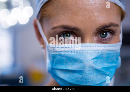 Ritratto di donna chirurgo indossando maschera chirurgica nel teatro di funzionamento Foto Stock