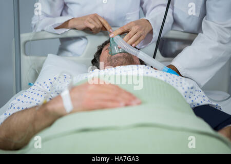 Medico posizionando una maschera ad ossigeno sulla faccia di un paziente Foto Stock