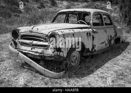 Zante, Grecia - 20 agosto 2016: il vecchio abbandonato auto arrugginite sorge nel giardino estivo, in bianco e nero Foto Stock