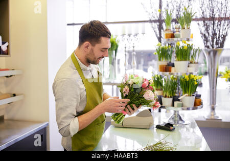 Fiorista sorridente uomo rendendo bunch al negozio di fiori Foto Stock