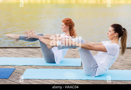 Donne che fanno yoga a mezza barca pongono all'aperto Foto Stock