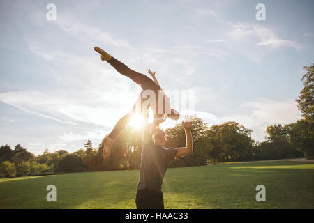 Sano giovane uomo e donna facendo varie yoga pone in coppia all'esterno. Montare il giovane facendo acroyoga nel parco. Foto Stock
