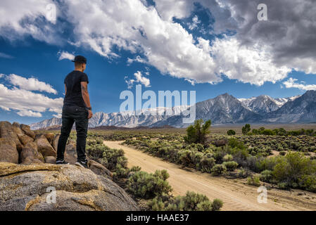 Giovane persona in piedi al di sopra di una strada sterrata in Alabama Hills in Sierra Nevada vicino a Lone Pine, CALIFORNIA, STATI UNITI D'AMERICA Foto Stock
