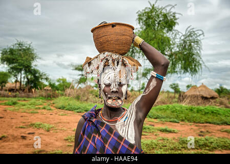 Una donna dalla tribù africana Mursi con grande piastra a labbro e con un cestello sul suo capo Foto Stock