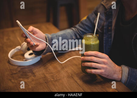 Uomo che utilizza il cellulare mentre avente succhi di frutta Foto Stock