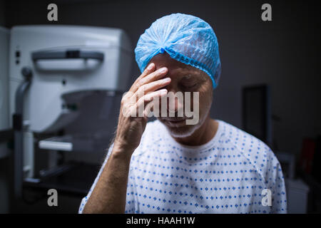 Triste paziente con la mano sulla testa in x-ray room Foto Stock