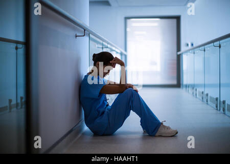 Triste infermiere seduto in corridoio Foto Stock