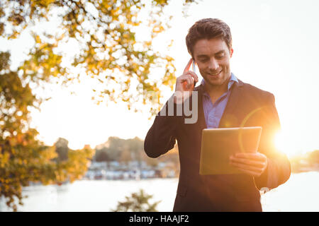 Imprenditore parlando al telefono cellulare mentre si utilizza tavoletta digitale Foto Stock