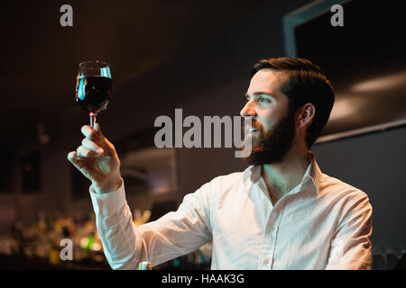 Barista guardando il bicchiere di vino rosso Foto Stock