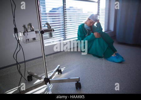 Teso chirurgo femmina seduto in corridoio Foto Stock
