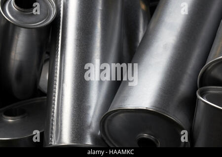 Background Industriale. Pile di nuovi scarichi e silenziatori marmitte auto prima della distribuzione e della vendita al dettaglio. Dettaglio di un nuovo automot Foto Stock