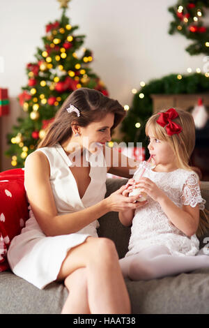 Madre passando bottiglia di latte alla figlia Foto Stock