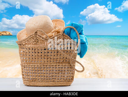 Beach basket impaccata con asciugamano e cappello con spiaggia blur sullo sfondo Foto Stock