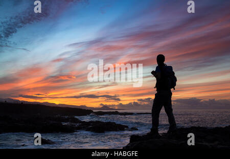 Las Palmas de Gran Canaria, Isole Canarie, Spagna. 29 Nov, 2016. Meteo: Come temperature di congelamento ha colpito la maggior parte del Regno Unito, è un glorioso tramonto nelle isole Canarie - un popolare sole invernale destinazione per molti inglesi - come un escursionista si stagliano contro un cielo mozzafiato sulla costa nord di Gran Canaria. Credito: Alan Dawson News/Alamy Live News Foto Stock