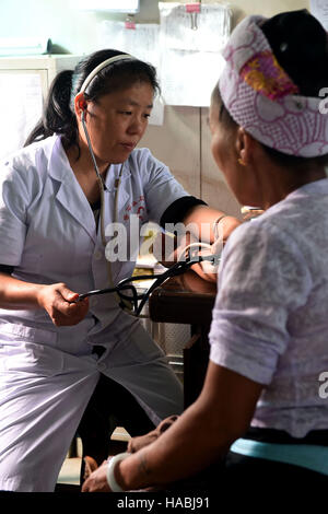 (161130) -- KUNMING, nov. 30, 2016 (Xinhua) -- Medico Yin Zuluan controlli di una donna e la pressione del sangue in una clinica nel villaggio Guangsong, Dehong dai, e Jingpo prefettura autonoma, a sud-ovest della Cina di Provincia di Yunnan, Ottobre 17, 2016. Yin Zuluan la famiglia ha pensato che fosse abbastanza testardo come ha rifiutato di prendere in considerazione i loro ripetuti suggerimenti per chiudere il suo lavoro di medico in un remoto villaggio nella provincia di Yunnan. Per 19 anni, Yin ha passato la maggior parte del suo tempo nel villaggio Guangsong, visitando i suoi pazienti HIV positivi e la sensibilizzazione degli abitanti del villaggio sulle modalità di controllo del virus mortale. La villa Foto Stock