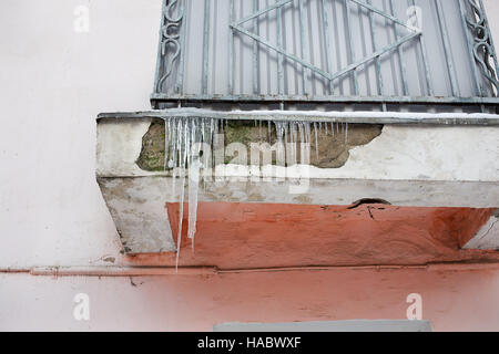 Ghiaccioli su grigio balcone di casa vecchia Foto Stock