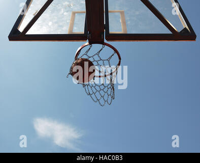 Una palla da basket swishes attraverso il cerchio guardando dal di sotto. Foto Stock