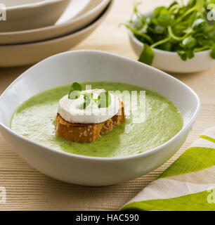 Una ciotola di zuppa di crescione, guarnite con fette di pane abbrustolito e formaggio di capra. Foto Stock