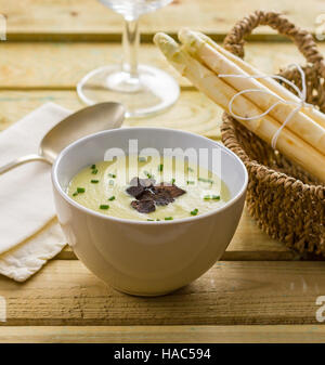 In casa la zuppa di asparagi in una ciotola, guarnita con erba cipollina e tartufo nero. Foto Stock