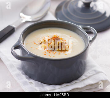 Zuppa cremosa in una piccola cucina in ceramica pentola, guarnita con legno di noce. Foto Stock