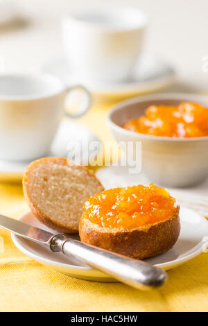 Deliziosa pesca e arancio marmellata su un panino su un tavolo per la colazione. Foto Stock