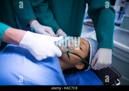 I chirurghi regolando le maschere di ossigeno sulla bocca del paziente nel teatro di funzionamento Foto Stock
