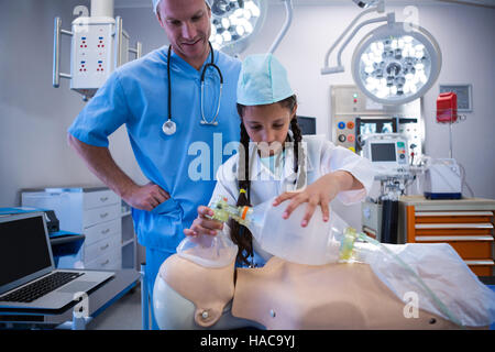 Medico assiste una ragazza nel porre un ossigeno su fantoccio Foto Stock