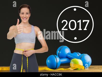 Donna misurando la sua vita contro 2017e mostrando pollice in alto Foto Stock
