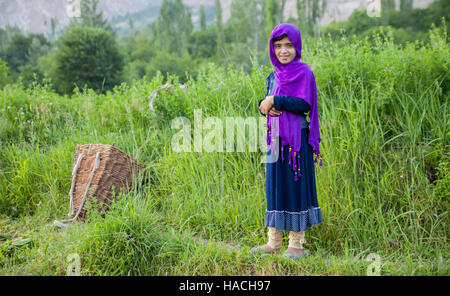 Ragazza pakistana in tradizionale costume musulmano in piedi sul campo dove lei ottiene l'erba alla alimentazione del bestiame Foto Stock