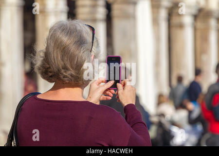 Le donne che prendono le foto sul suo telefono cellulare, in Piazza San Marco, Venezia, Italia. Foto Stock