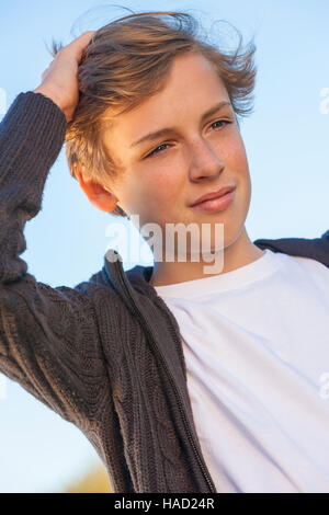 Giovani felici di ridere maschio ragazzo adolescente bionda bambino fuori nel sole estivo bianco che indossa la t-shirt Foto Stock