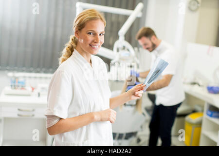 Femmina specialista dentale esamina un x-ray del dente mentre in background donna ha il dentista checkup Foto Stock