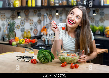 Donna con insalata in cucina Foto Stock