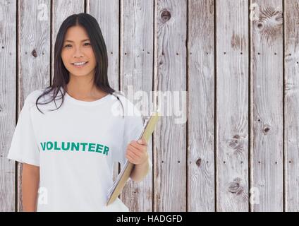 Volontari femmina tenendo un clipboard contro lo sfondo di legno Foto Stock