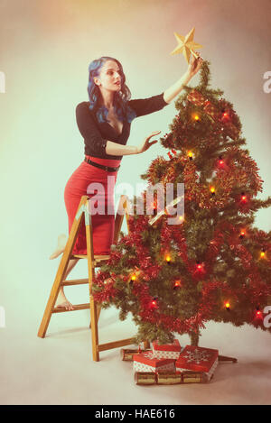 Vintage stile cartolina immagine della donna mettendo una stella d'oro  sull'albero di Natale Foto stock - Alamy