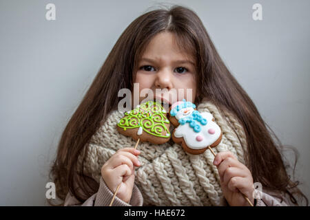 Bellissima ragazza con lunghe parentesi marrone capelli in un fazzoletto bianco mangiare di panpepato di Natale. Foto Stock