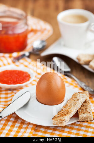 Uova sode con caviale rosso, pane tostato e caffè per colazione Foto Stock