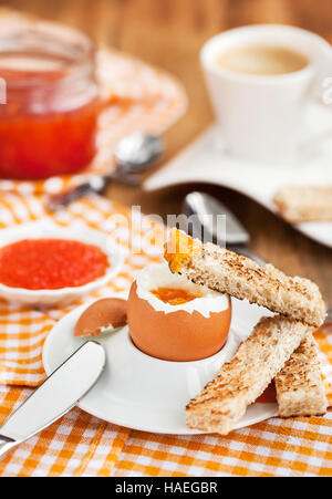 Uova sode con caviale rosso, pane tostato e caffè per colazione Foto Stock