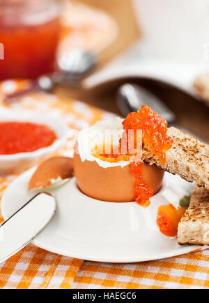 Uova sode con caviale rosso, pane tostato e caffè per colazione Foto Stock