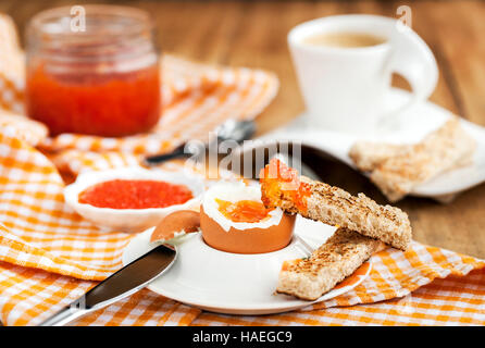 Uova sode con caviale rosso, pane tostato e caffè per colazione Foto Stock