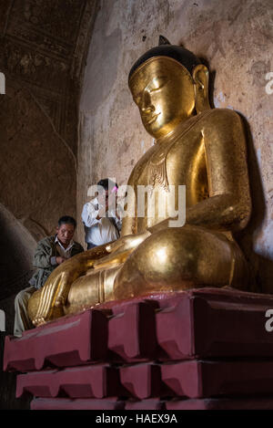 Persone che diano alle offerte di un Golden statua del Buddha presso il Tempio Sulamani a Bagan, Myanmar. Foto Stock